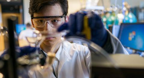 Student pouring liquid into chemical flask